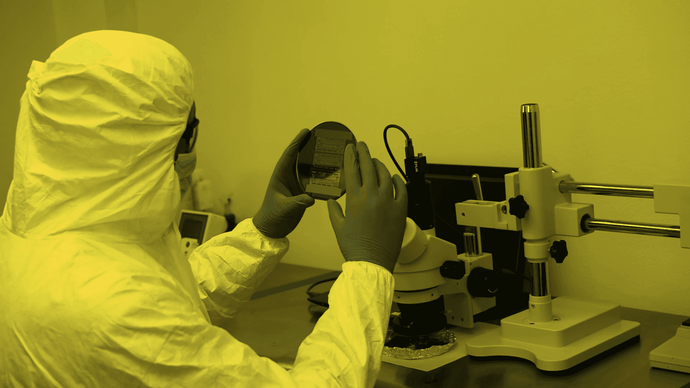Researcher in yellow PPE at microscope